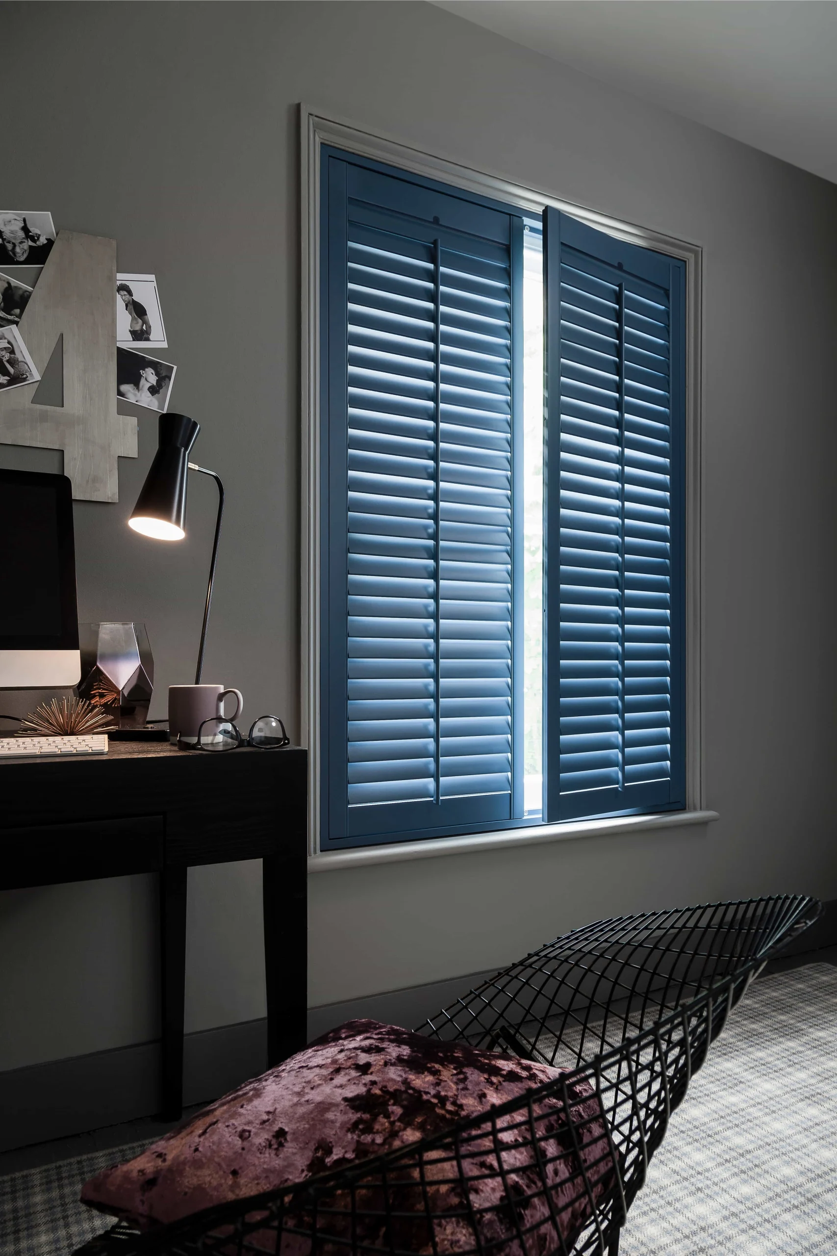 Deep blue plantation shutters closed across a bedroom window in a contemporary interior.