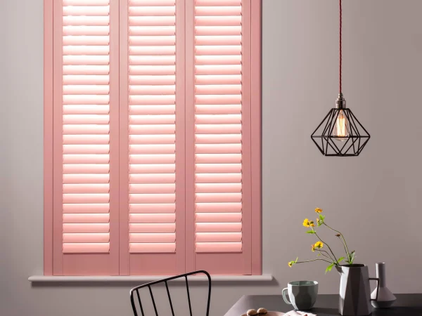 Coral blush full-height plantation shutters fitted in a contemporary dining room with geometric flooring.