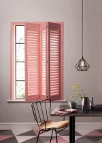 Coral blush plantation shutter panels opened to reveal the window in a modern dining room.