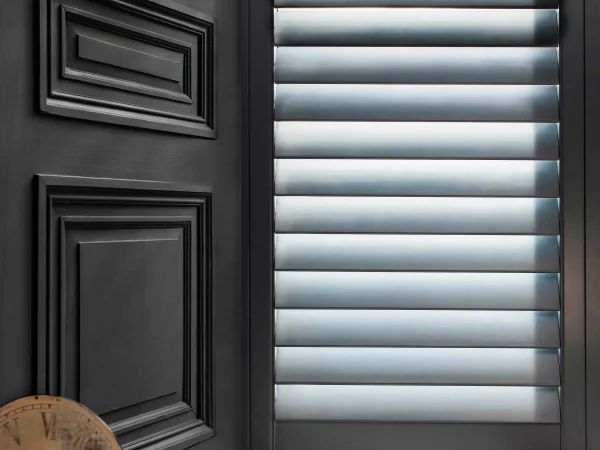 Formal blue plantation shutters fitted beside dark decorative wall panelling in an elegant interior.