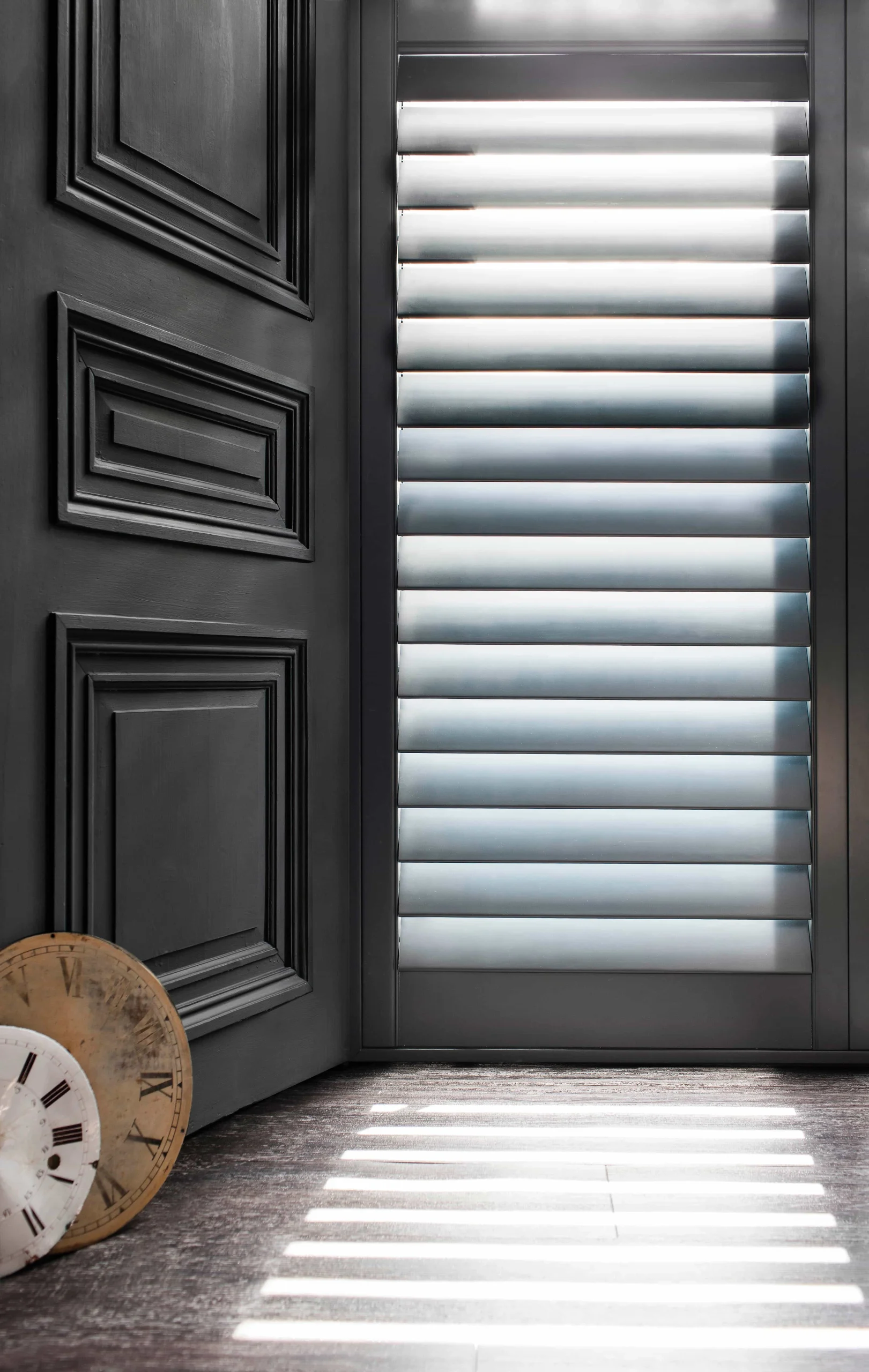 Formal blue plantation shutters fitted beside dark decorative wall panelling in an elegant interior.