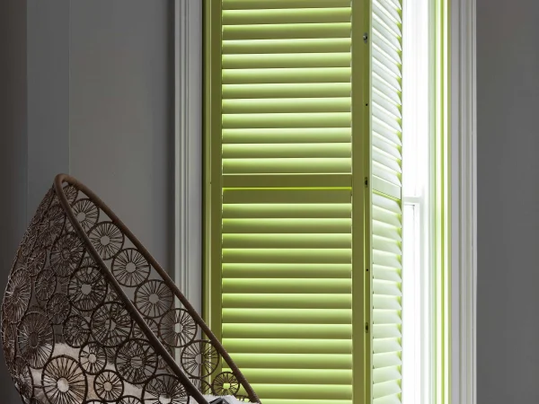 Lime green plantation shutters with one panel opened in a bright contemporary room.
