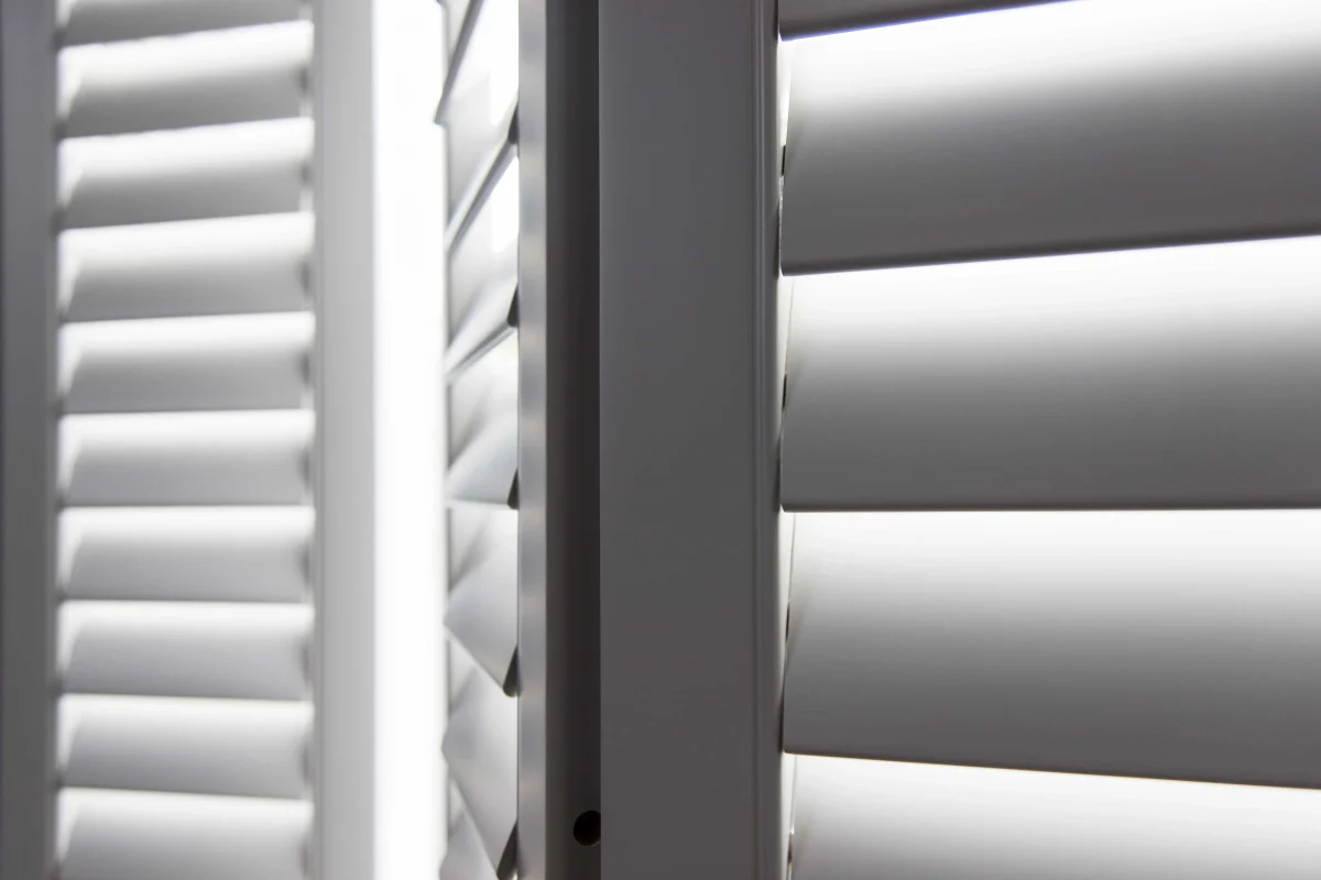 Close-up of taupe plantation shutter louvres, frame and panel edges.
