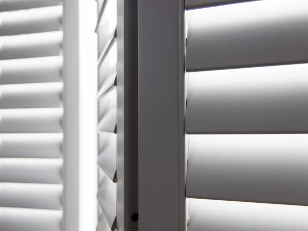 Close-up of taupe plantation shutter louvres, frame and panel edges.