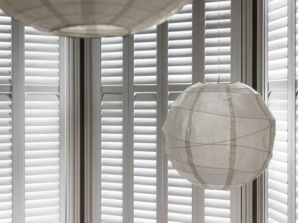 Taupe plantation shutters fitted around a curved bay window with multiple panels.
