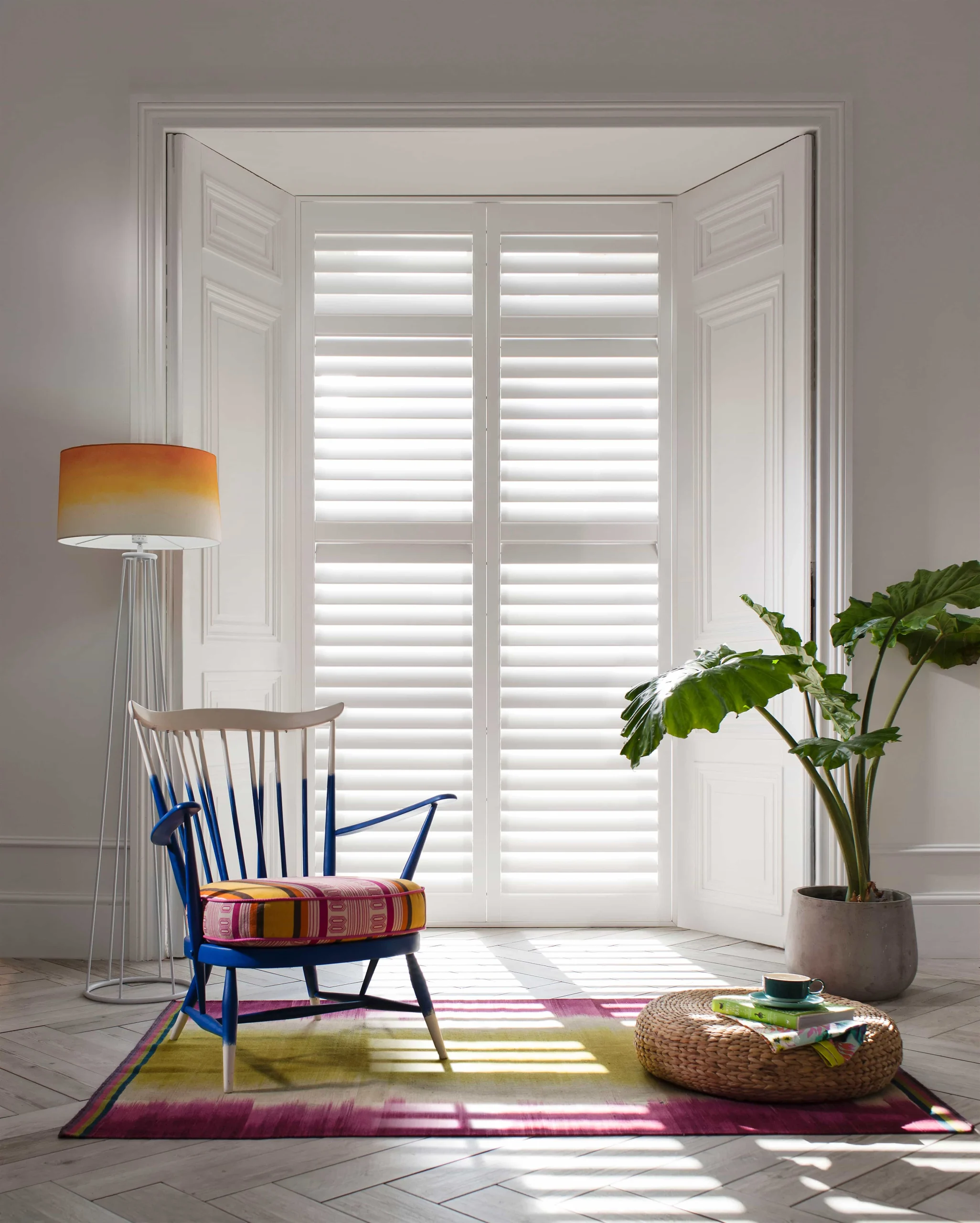 White plantation shutters fitted to a shallow bay window in a modern living area.